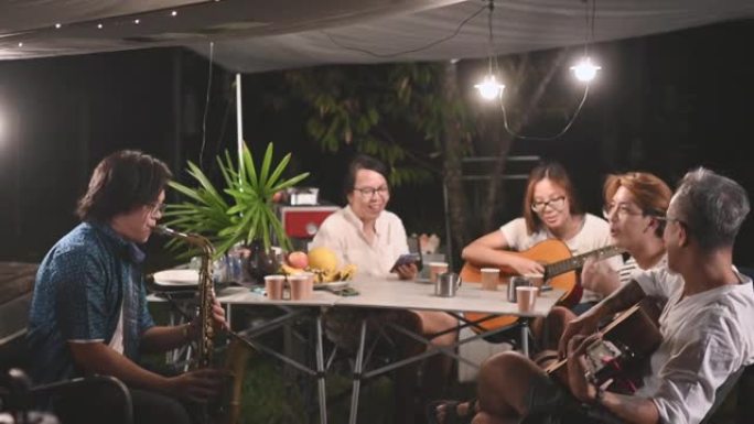 亚洲华人家人和朋友晚上喜欢玩乐器花园派对聚会露营帐篷