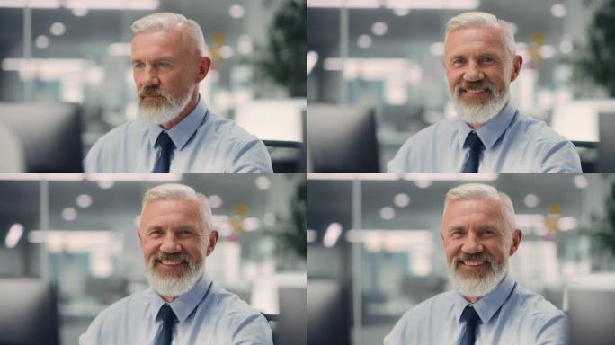 一位自信快乐的高级男性穿着蓝色衬衫，看着相机，真诚迷人地微笑着。成功经验丰富的老人在不同的公司办公室