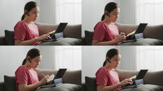 年轻女子在家工作时使用笔记本电脑和手机