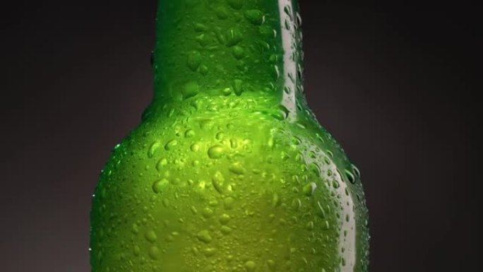 绿色冷瓶，配有啤酒、水或软饮料。装有水滴和冷凝水的瓶子。冷光精酿啤酒。镜头中的旋转缩放
