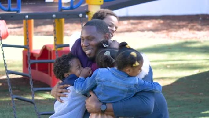 混合种族的父亲在操场上拥抱他的四个孩子