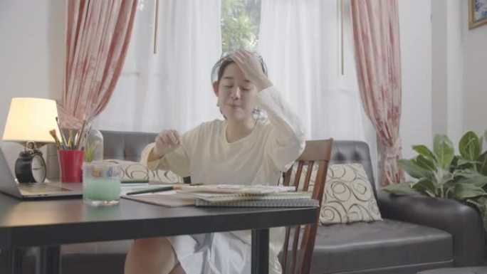 POV手持宽镜头亚洲少女在客厅手绘和绘画她的艺术。她使用笔记本电脑与朋友进行视频通话，同时使用水彩和