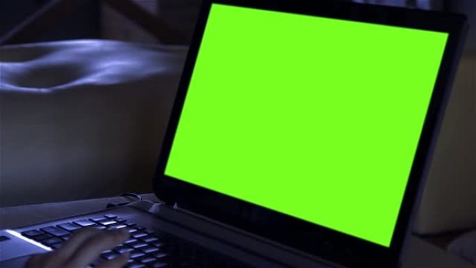 暗室绿屏笔记本电脑。特写。您可以用所需的素材或图片替换绿色屏幕。您可以在After Effects或