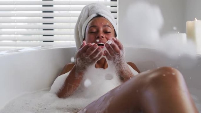 非裔美国妇女在家里浴室的浴缸里吹肥皂泡