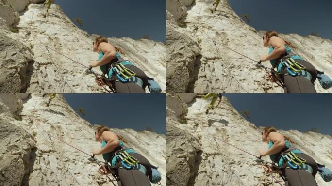 自下而上: 女性belayer帮助攀岩者攀登岩石悬崖。