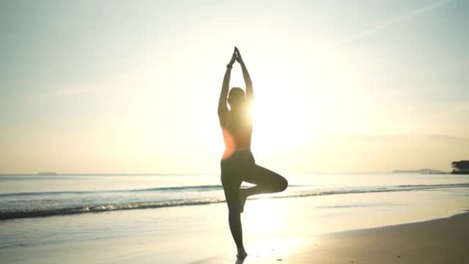 日落时在沙滩上练习瑜伽的亚洲女性