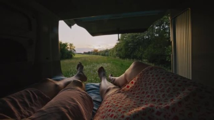 WS夫妇躺在黄昏时停在草地上的露营者的小屋里