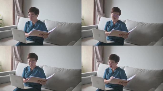 在家工作的亚洲华裔女医生在客厅使用笔记本电脑咨询她的成年高龄患者