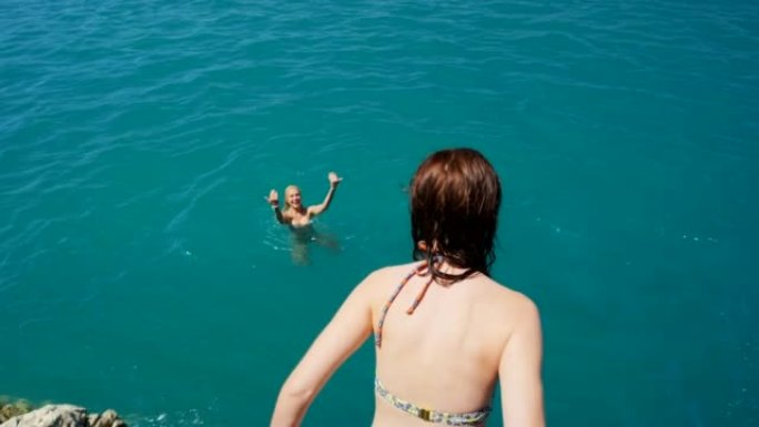 4k视频片段，一名年轻女子从悬崖上跳入大海