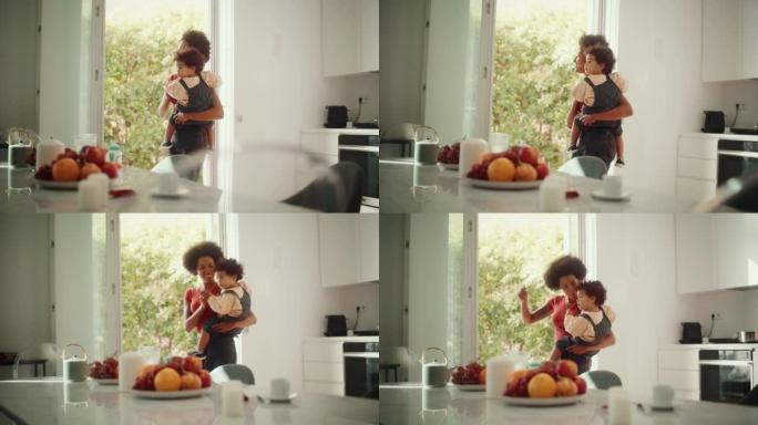 快乐的母亲抱着可爱的男婴，在家里的客厅玩耍，玩耍。非洲裔美国女性手臂上抱着活跃的蹒跚学步的儿子跳舞。