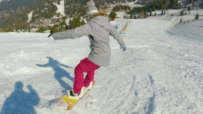 年轻女性学习骑滑雪板并在下雪的滑雪场上转弯