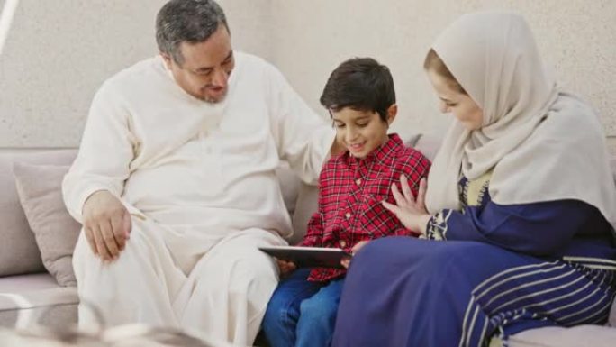 坐在祖父母之间的数字平板电脑的沙特男孩