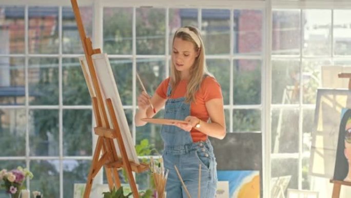 创意女艺术家在艺术工作室里画一个形象。艺术画家在画布上使用画笔创作一幅画。年轻的设计师在周末在家做她