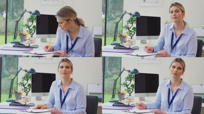 办公室里成熟的女医生坐在办公桌前在剪贴板上做笔记，然后看着慢动作镜头