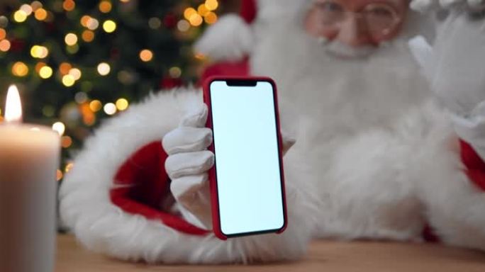圣诞老人的特写镜头在相机中显示智能手机的空屏幕，并显示拇指向上，