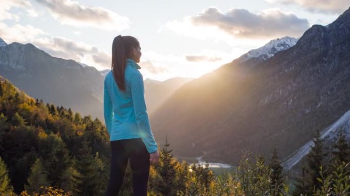 健康导向的女人站在山顶上，在日落时欣赏山谷的壮丽景色