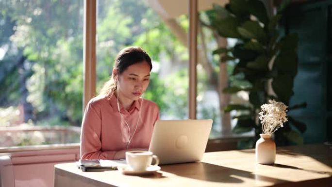 亚洲妇女在咖啡馆使用笔记本电脑