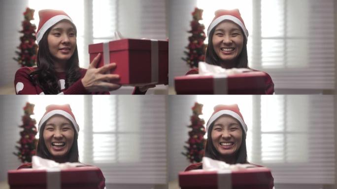 亚洲女人指着圣诞礼盒，手里拿着和展示礼盒