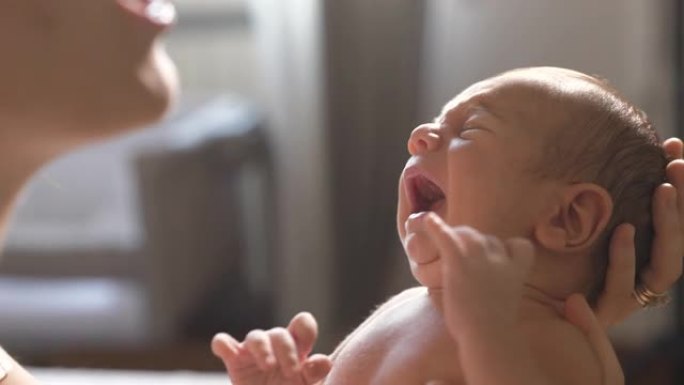 一位母亲在哭泣时抱着她的新生婴儿并与之交谈的慢动作镜头。一个刚成为母亲的女人的真实镜头，试图通过与他