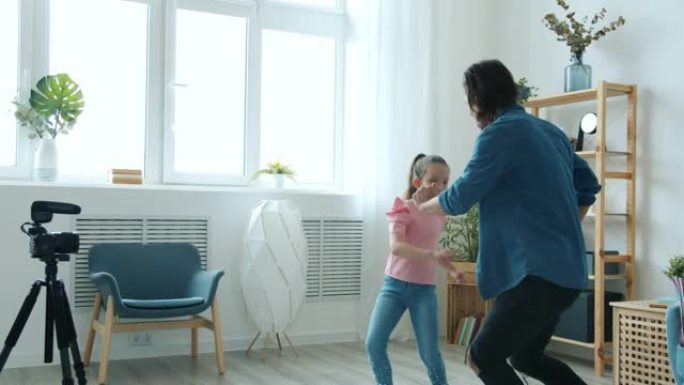 父亲和孩子的博客们跳舞和挥舞着手，就像为摄像机摆姿势一样