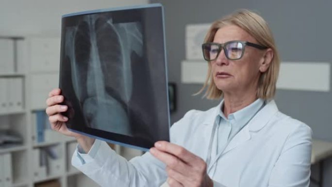 经验丰富的女放射科医生戴眼镜看肺部x线图像