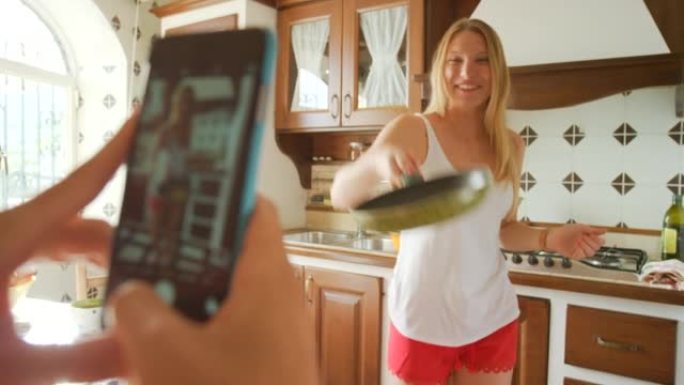 一个兴奋的年轻女子在用手机拍照时翻转煎饼