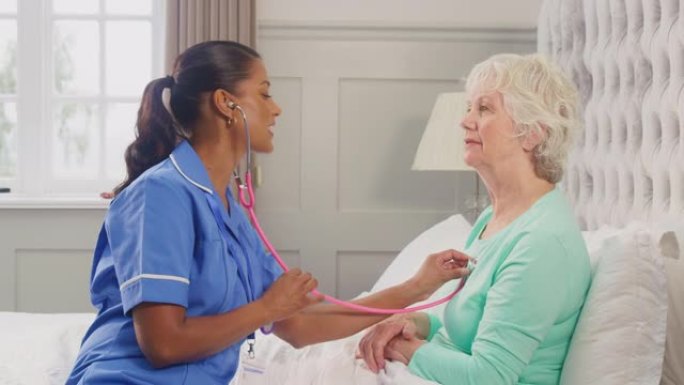穿着制服的女护理人员在床上用听诊器听老年妇女的胸部