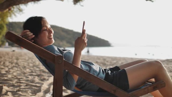 亚洲妇女在海滩上使用电话