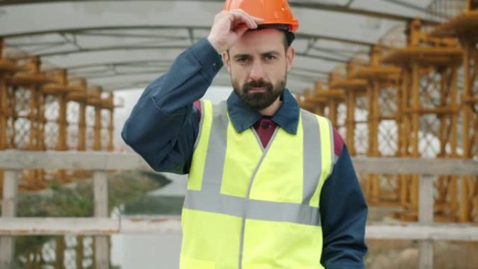 建筑工人戴上安全帽，交叉手臂站在建筑区域