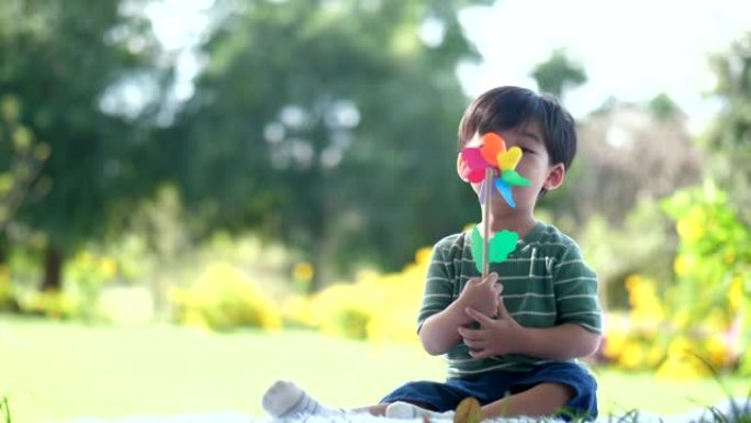 男孩坐在花园里玩玩具风车