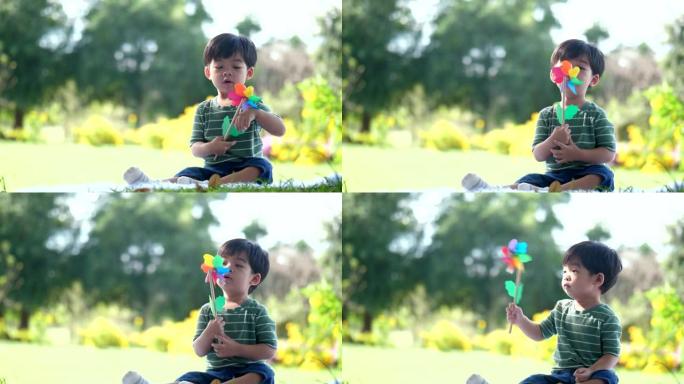 男孩坐在花园里玩玩具风车