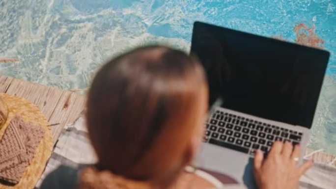 SLO MO女人用腿踢水时使用笔记本电脑