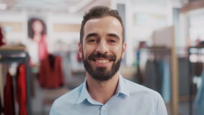 一位穿着蓝色衬衫的快乐英俊的店员在服装店微笑着摆姿势拍照的肖像。小企业主，担任商人或销售经理的角色。