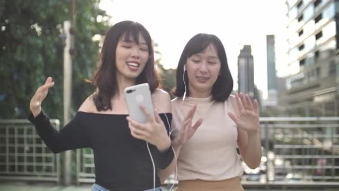 两个亚洲女人一起跳舞唱歌，欣赏音乐