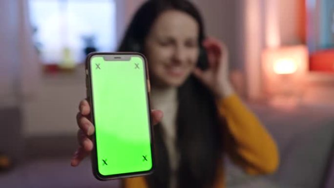 年轻女子用手指指着智能手机的色度键屏幕