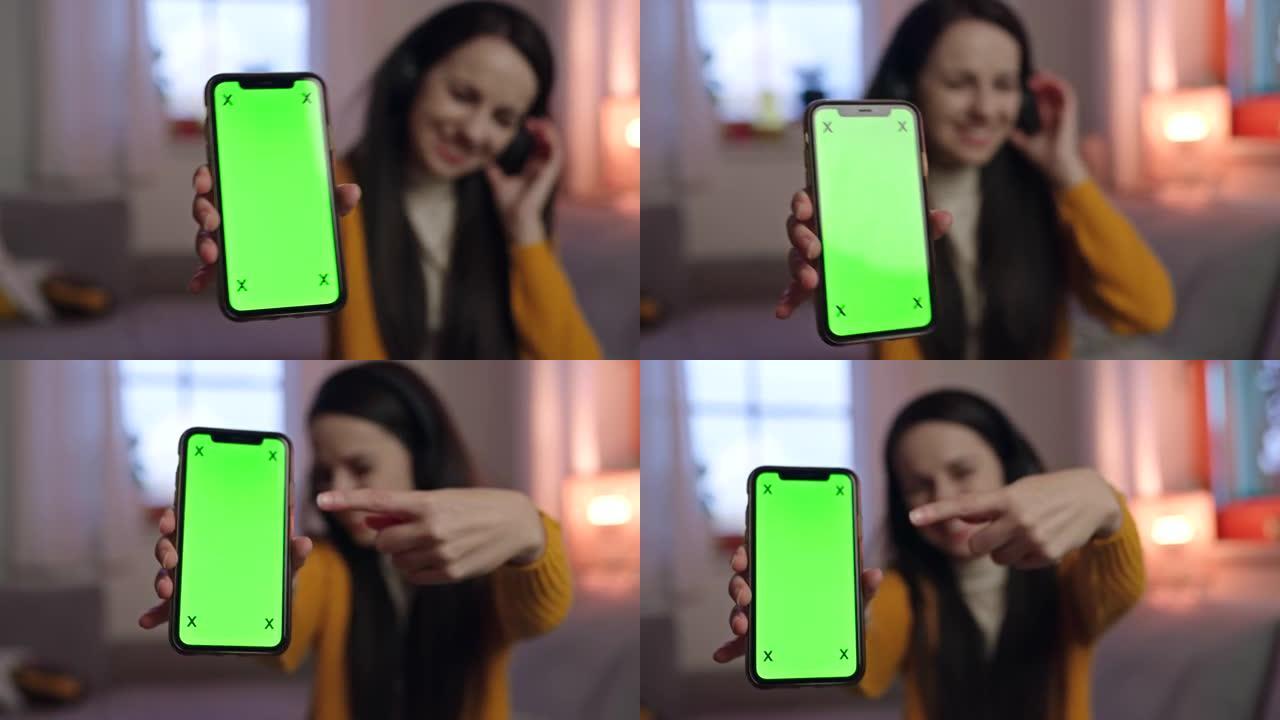 年轻女子用手指指着智能手机的色度键屏幕