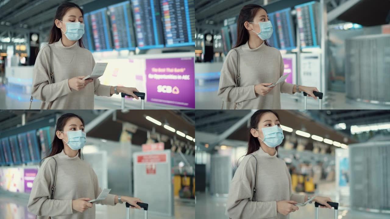 年轻的女旅行者戴着外科口罩，在电子时刻表上检查登机时间