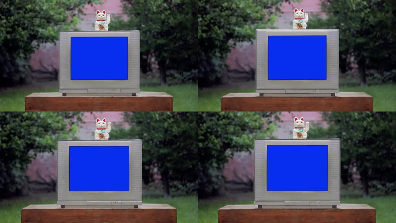 Maneki Neko幸运猫和带蓝屏的旧电视。