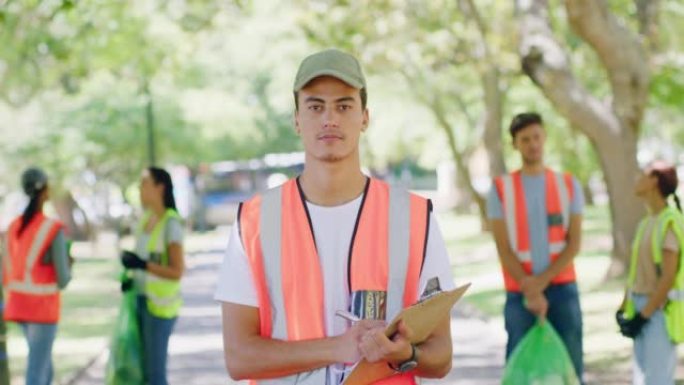 一名年轻的环保非政府组织雇员在公园清洁项目的肖像。一群身穿制服的志愿者在公园里工作。在田野里一起捡垃