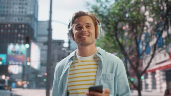一个英俊的年轻人的肖像随便走在街上，用智能手机的耳机听音乐。他在大城市中使用电话，向人们发送在线消息