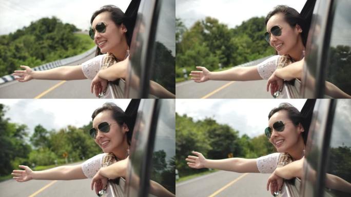 亚洲妇女将手伸出车窗，微笑着。慢动作