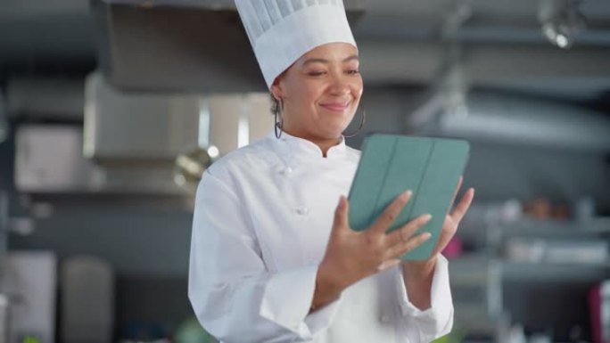 餐厅厨房: 黑人女厨师烹饪美味正宗的食物，使用数字平板电脑。专业人士创造传统菜肴，使用健康成分，准备
