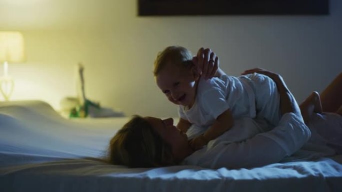 一位年轻快乐、和平的新妈妈在床上睡着之前，正在和她刚出生的男婴一起享受时光