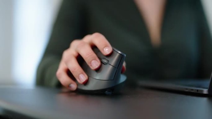 使用笔记本电脑键盘和桌子上的无线鼠标的女人的手的特写