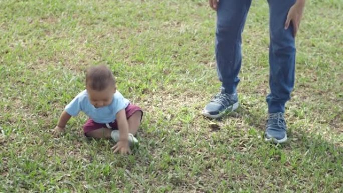 SLO MO快乐的男婴试图迈出一步，跌倒在草地上