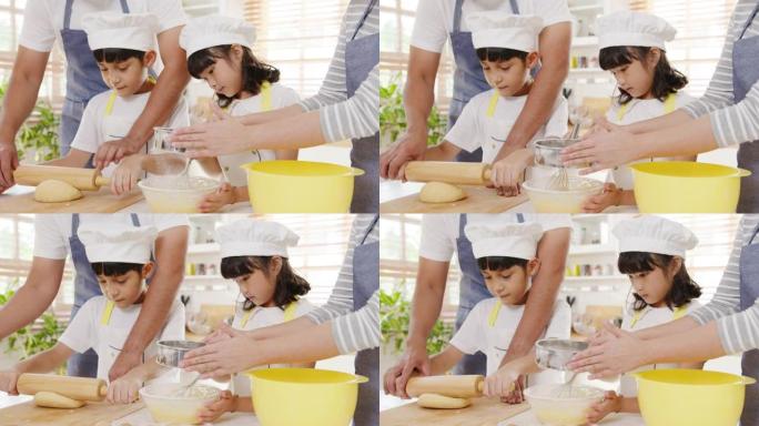快乐微笑的年轻亚洲日本家庭与学龄前儿童有乐趣烹饪烘焙糕点或馅饼在早上的现代厨房家庭早餐。