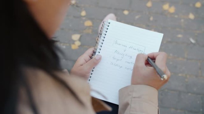 年轻企业家计划创业战略时，女性手写笔记本的特写