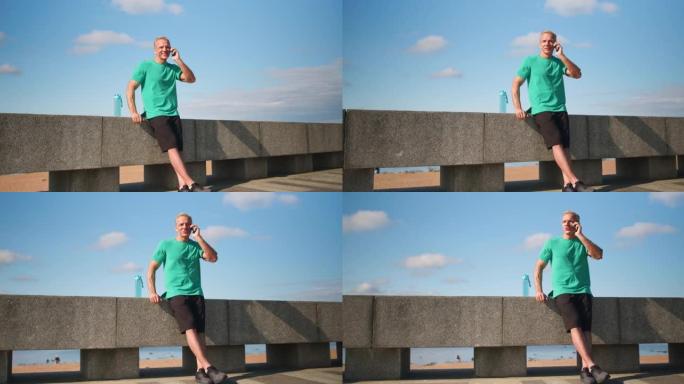 一位金发碧眼的斯堪的纳维亚跑步者正靠在路堤的石栏上，在电话上完成了对话。