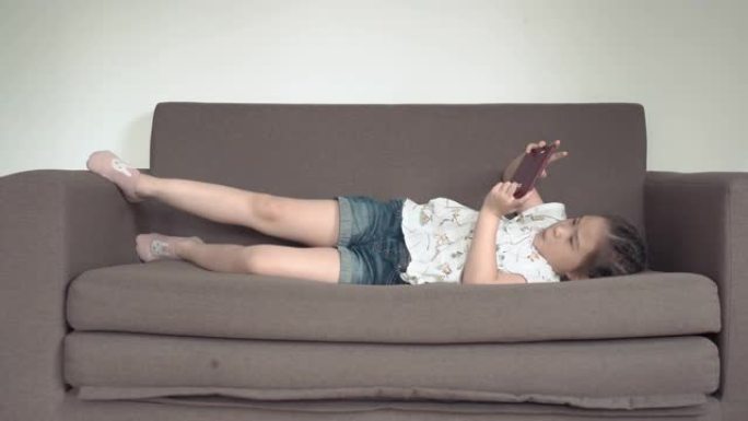 儿童小女孩使用智能手机在客厅沙发上放松