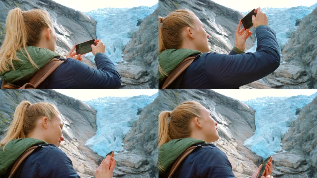 4k视频片段，一名年轻女子站着并用手机拍摄Briksdal冰川
